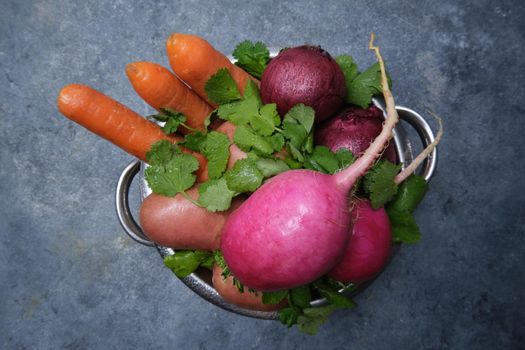 Turnip, cilantro, potatoes, carrots and red onions on a dark background