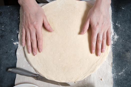 Women's hands knead the dough from wheat flour