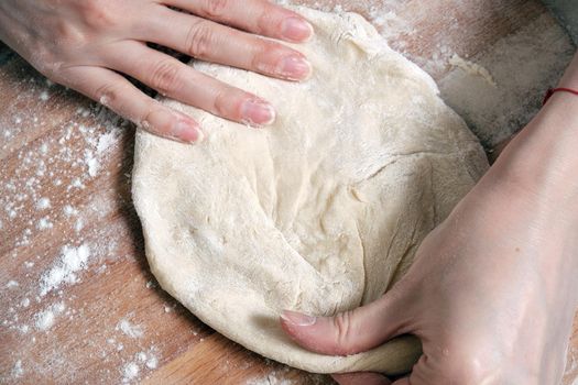 Women's hands knead the dough from wheat flour