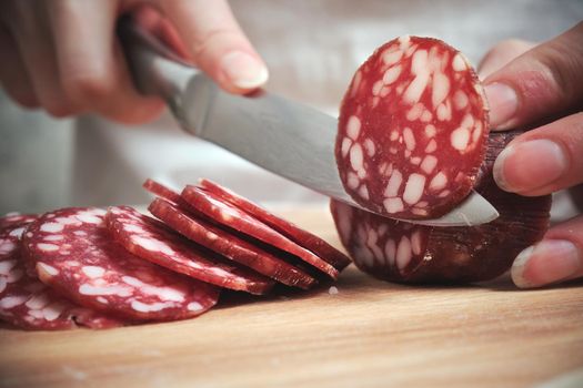 The knife cuts the smoked sausage into pieces