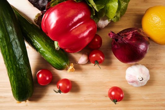 Cucumber, tomatoes, peppers, garlic and lettuce on a dark background