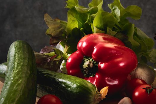 Cucumber, tomatoes, peppers, garlic and lettuce on a dark background