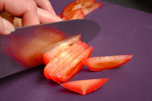 Slicing tomatoes on a cutting board with a knife