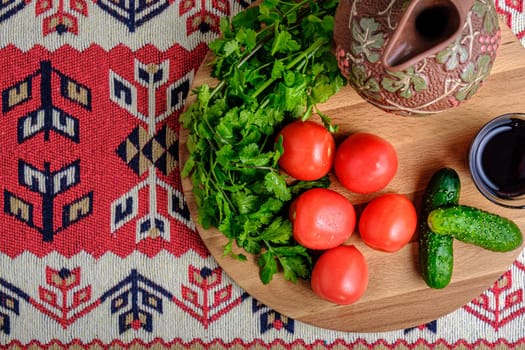 Tomatoes, cucumbers, herbs, a jug and wine on a wooden tray