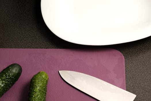 Plate, knife, cucumbers and cutting board