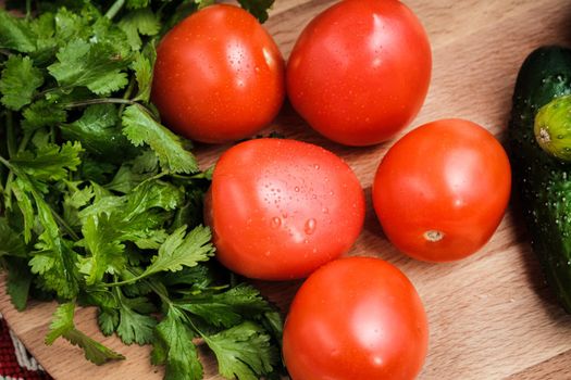 Tomatoes, cucumbers and herbs on a cutting board