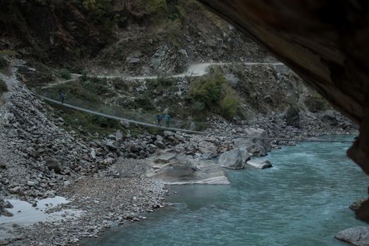 Three backpackers walking across a suspension bridge over the Marshyangdi river, Annapurna circuit, Nepal