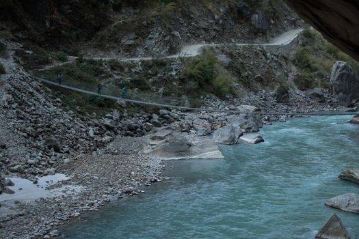 Three backpackers walking across a suspension bridge over the Marshyangdi river, Annapurna circuit, Nepal