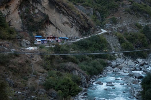 Nepalese mountain village by a suspension bridge over the Marshyangdi river gorge valley, Annapurna circuit, Himalaya, Nepal, Asia