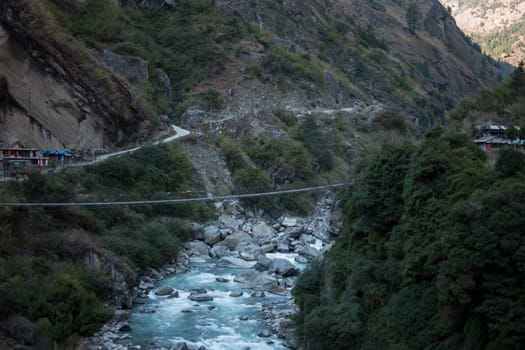 Nepalese mountain village by a suspension bridge over the Marshyangdi river gorge valley, Annapurna circuit, Himalaya, Nepal, Asia