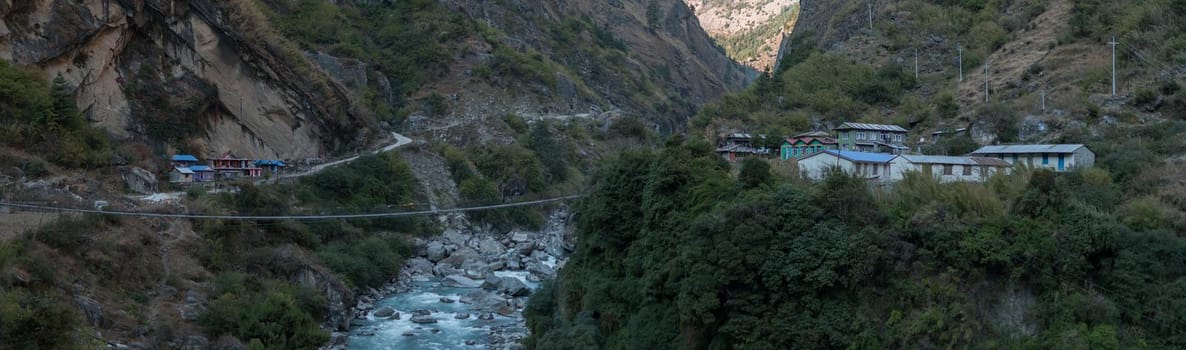 Panorama of nepalese mountain village by a suspension bridge over the Marshyangdi river gorge valley, Annapurna circuit, Himalaya, Nepal, Asia