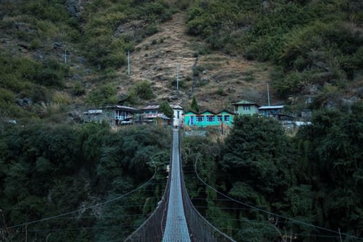 Nepalese mountain village by a suspension bridge over the Marshyangdi river gorge valley, Annapurna circuit, Himalaya, Nepal, Asia