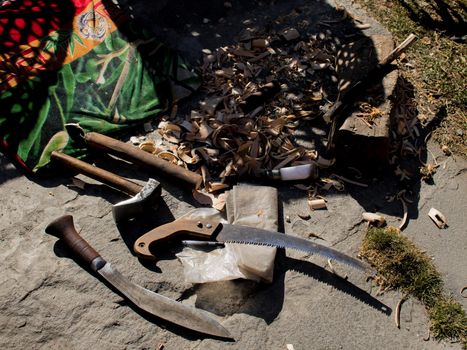 A saw, knife and a hammer tools outdoors on rock floor