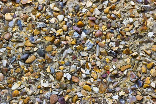 A rough pebble dash covering on an external wall showing small stones of various shapes and colours