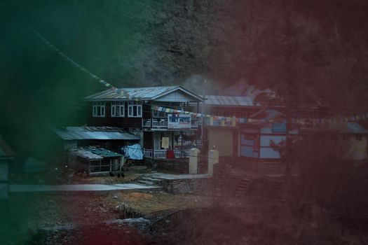 Chame mountain village seen through colorful buddhist prayer flags, trekking Annapurna circuit, Nepal