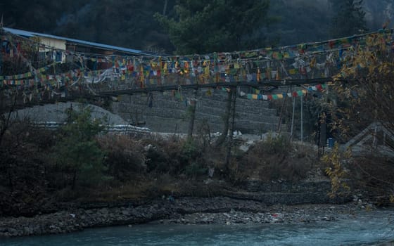 Chame suspension bridge colorful buddhist prayer flags over Marshyangdi river, Annapurna circuit, Nepal