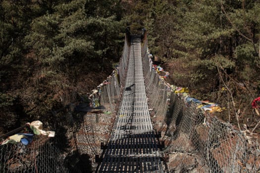 Trekking Annapurna circuit, suspension bridge with buddhist prayer flags over Marshyangdi river