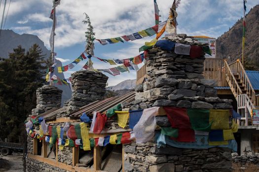 Colorful buddhist prayer flags on stone stupa monument, trekking Annapurna circuit, Himalaya, Nepal