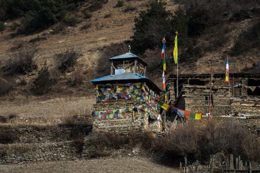 Colorful buddhist prayer flags stone monument, Upper Pisang, trekking Annapurna circuit, Himalaya, Nepal