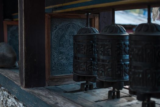 Close up of buddhist prayer wheels with sanskrit mantra and buddha painting