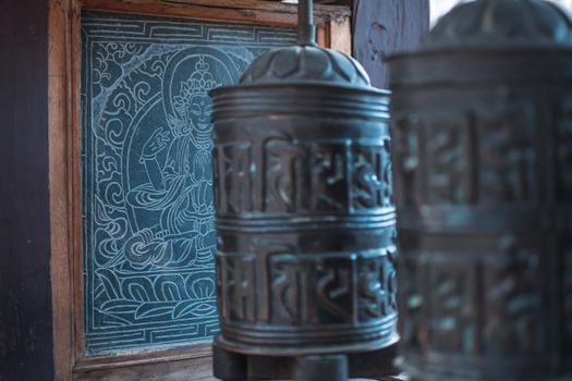 Close up of buddhist prayer wheels with sanskrit mantra and buddha painting