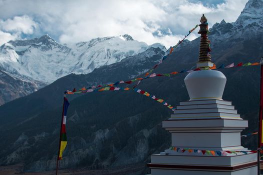 Buddhist stupa with prayer flags over Manang mountain village, trekking Annapurna circuit, Nepal