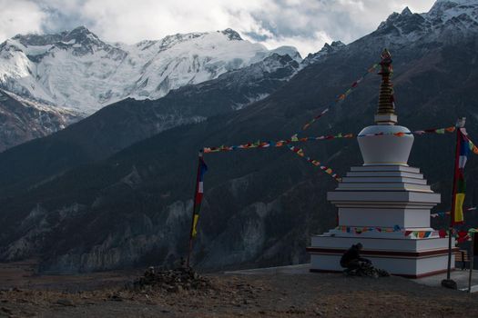Buddhist stupa with prayer flags over Manang mountain village, trekking Annapurna circuit, Nepal