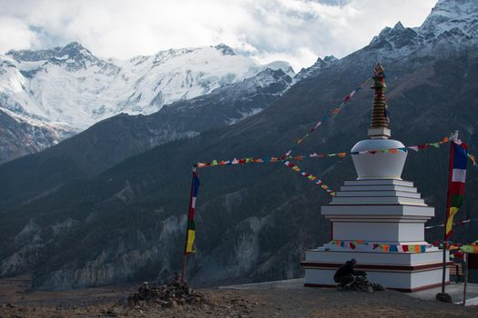 Buddhist stupa with prayer flags over Manang mountain village, trekking Annapurna circuit, Nepal