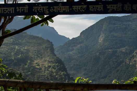Beautiful rolling mountains framed by a balcony with nepalese text written on it