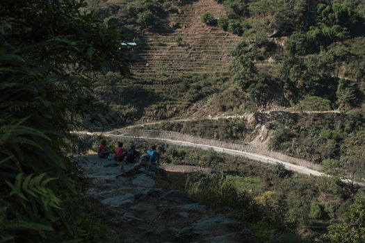 Four young teenagers resting at the edge of a cliff in Nepal