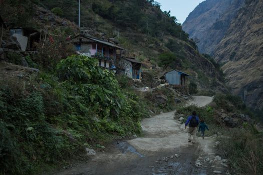 Father and son on a dirt road by beautiful mountain village, Annapurna circuit