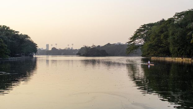 A man recreationally rowing solo for excercise and training in Rabindra Sarovar Lake, Minhaj Garden park, Kolkata, India