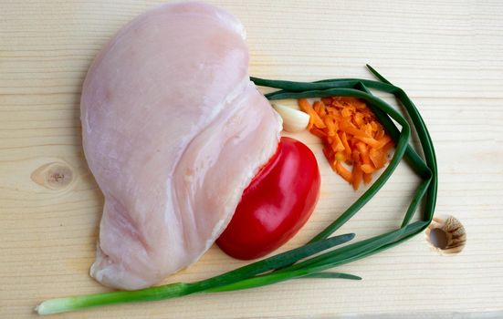 Raw chicken breast fillet on a white chopping board.