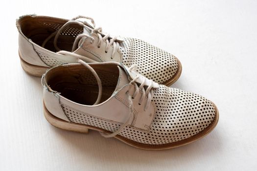 Close-up top view of old white leather shoes. The concept of repair and restoration work of a shoemaker-craftsman in a shoe repair shop.