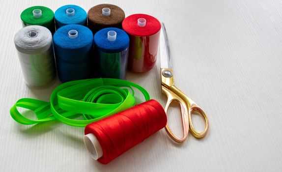 Colorful threads and scissors on a white background. Space for text