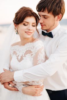 the groom gently hugs the bride from behind. High quality photo