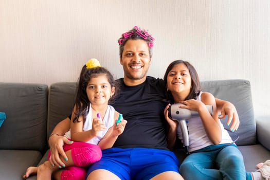 Pretty daughters are painting the nails and combing the hair of their handsome young father