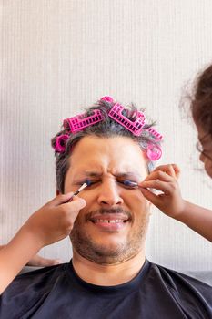 Handsome father is being makeup by the hands of his daughters