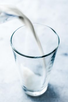 Dairy, healthy nutrition and breakfast concept - World Milk Day, pouring into glass on marble table