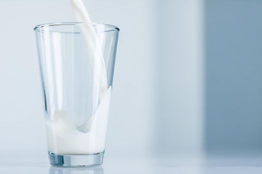 Dairy, healthy nutrition and breakfast concept - World Milk Day, pouring into glass on marble table