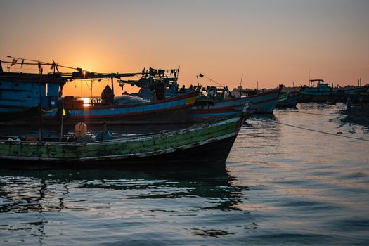 A orange beautiful sunset over colorful traditional wooden boats by the fishing society village Chaung Thar, Irrawaddy, western, Myanmar