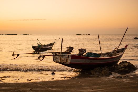 Two traditional wooden boats by the shore during a bright beautiful sunset close to Ngwesaung beach, Irrawaddy, western Myanmar