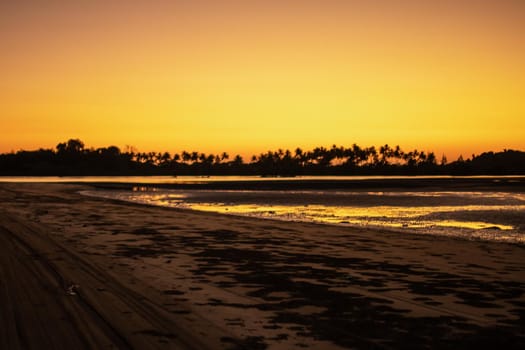 A sand beach during low tide and a bright orange sunset, peace and quiet, near Ngwesaung, Irrawaddy, western Myanmar