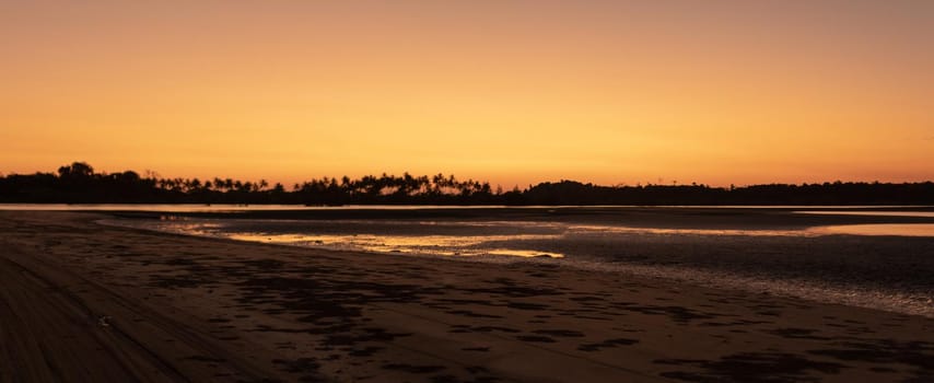 Panorama of a sand beach during low tide and a bright orange sunset, peace and quiet, near Ngwesaung, Irrawaddy, western Myanmar
