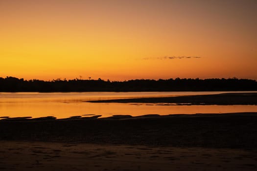A sand beach during low tide and a bright orange sunset, peace and quiet, near Ngwesaung, Irrawaddy, western Myanmar