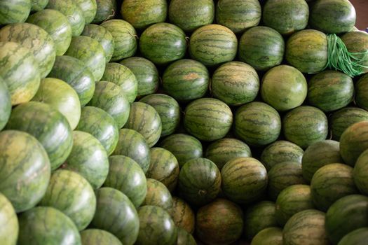 Big green fresh watermelons stacked in a huge pile at a local street market in Myanmar neat Yangon