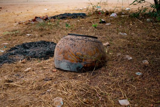 A borwn decorated and painted burmese clay pot broken and chipped in the grass in Bagan, Nyaung-U, Myanmar