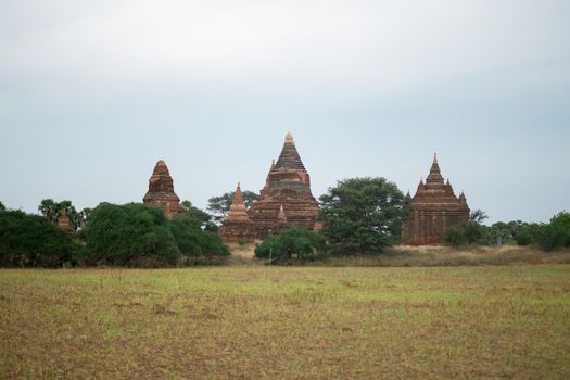 BAGAN, NYAUNG-U, MYANMAR - 2 JANUARY 2020: A few historical and religious pagoda temples from the old Pagan kingdom by a big field