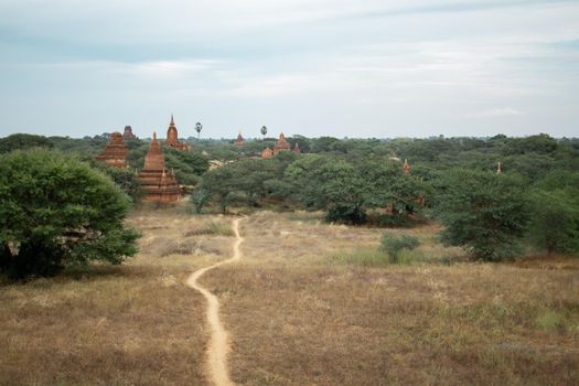 BAGAN, NYAUNG-U, MYANMAR - 2 JANUARY 2020: A dirt rail leading towards the historical buddhist temples in the distance