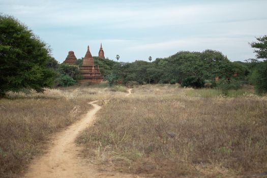 BAGAN, NYAUNG-U, MYANMAR - 2 JANUARY 2020: A dirt rail leading towards the historical buddhist temples in the distance